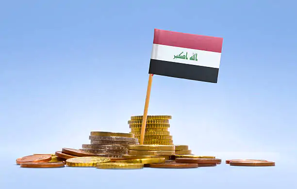 Flag of Iraq in a mixed stack of european coins and a blue background.(series) Government advisor: Iraq is in a prosperous and prosperous era despite the difficulties of the international economy.